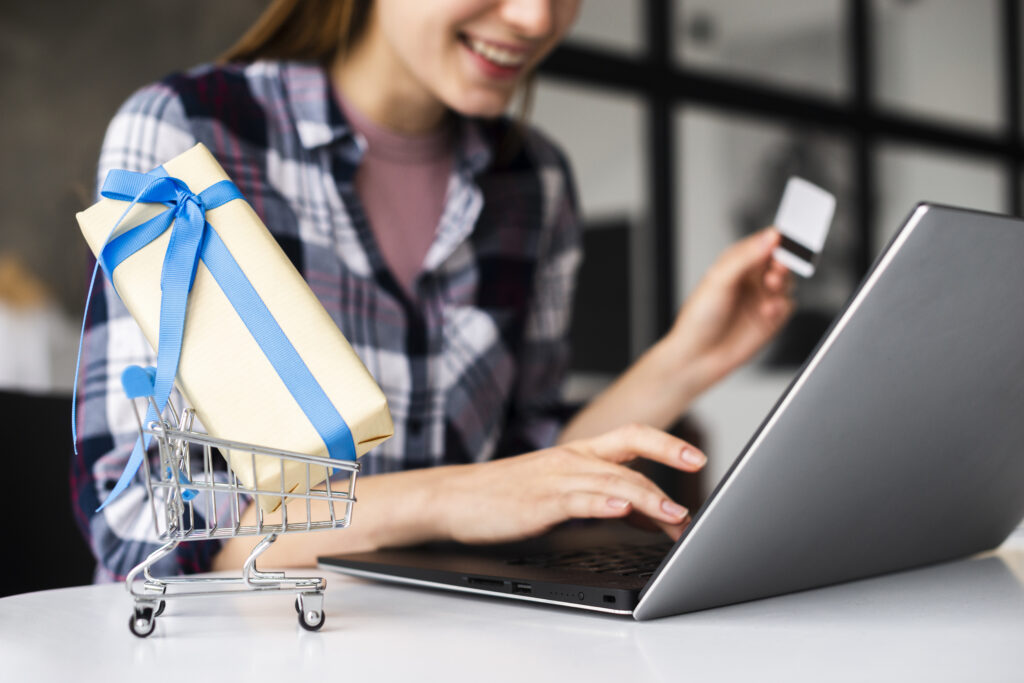 Mulher feliz olhando o computador com cartão de crédito nas mãos.